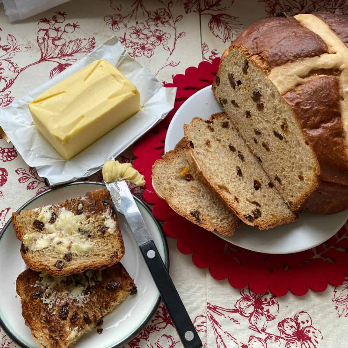 Hot Cross Bun Loaf with buttered slices on a plate.