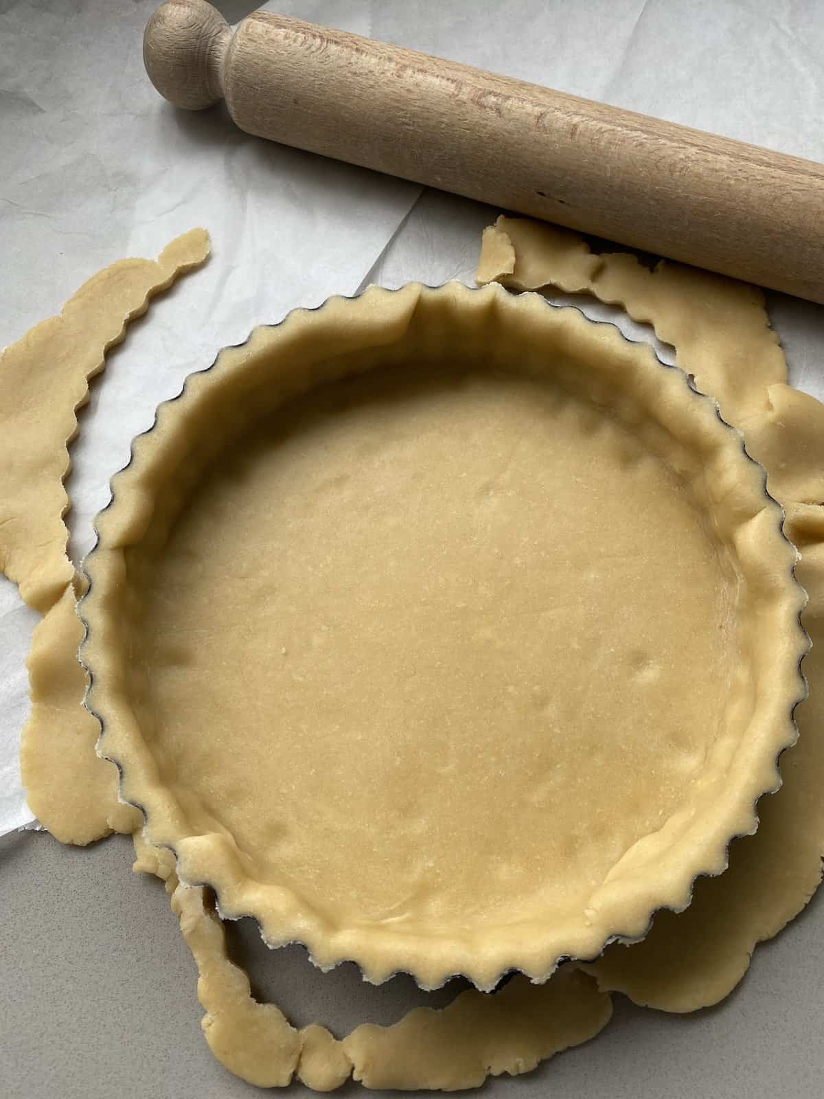 Uncooked pastry base with edges trimmed.