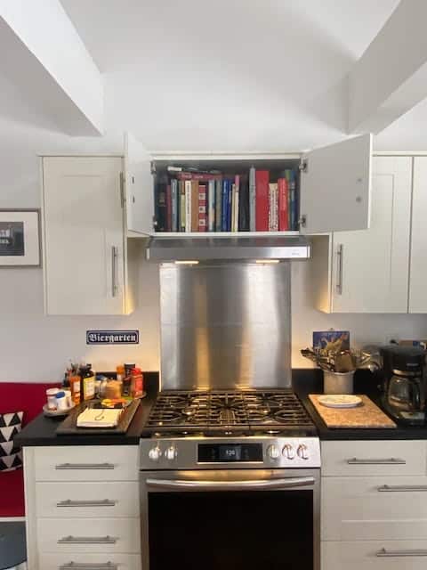 Kitchen cooker with a bookshelf above, on the wall. 
