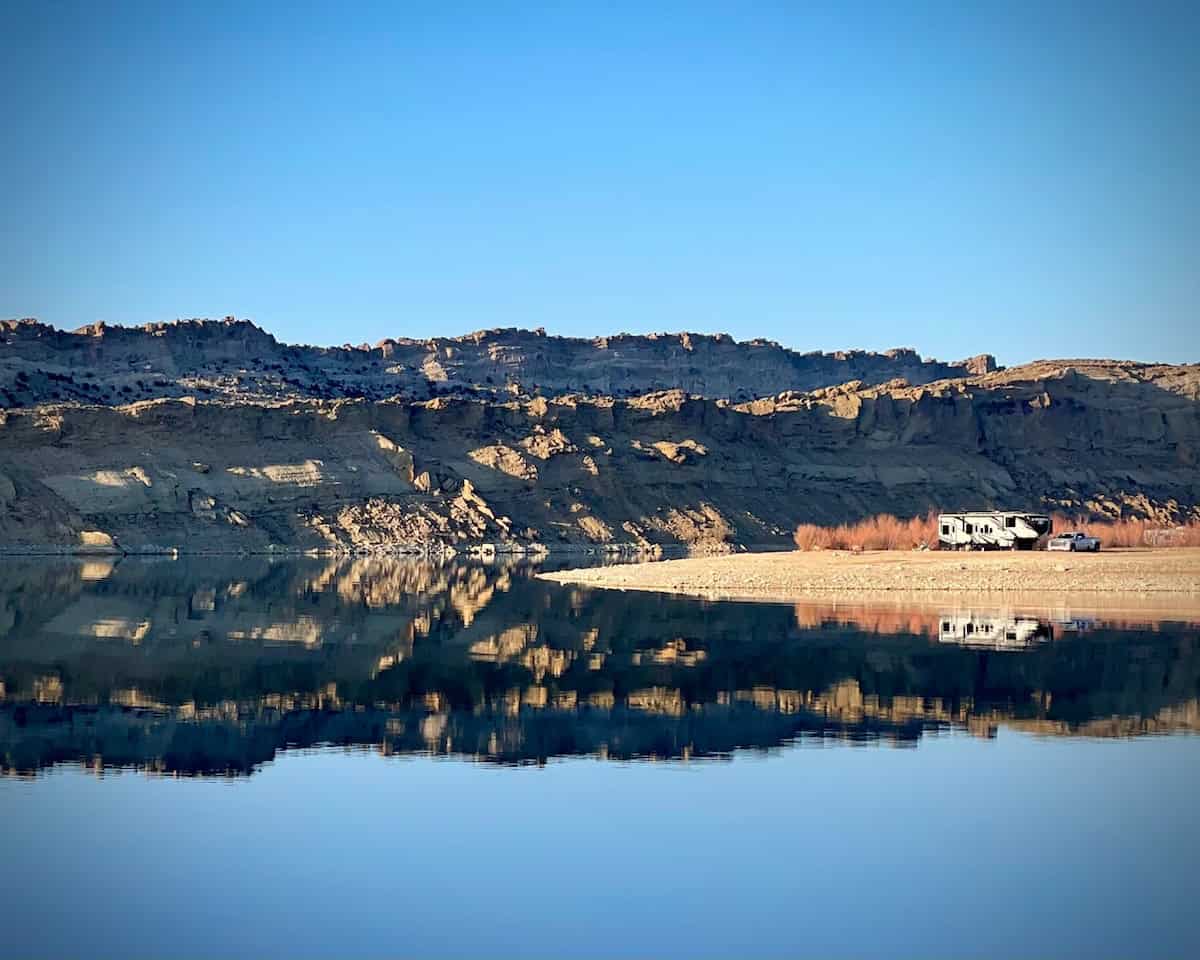 Lake and hillside, with an RV in the landscape.