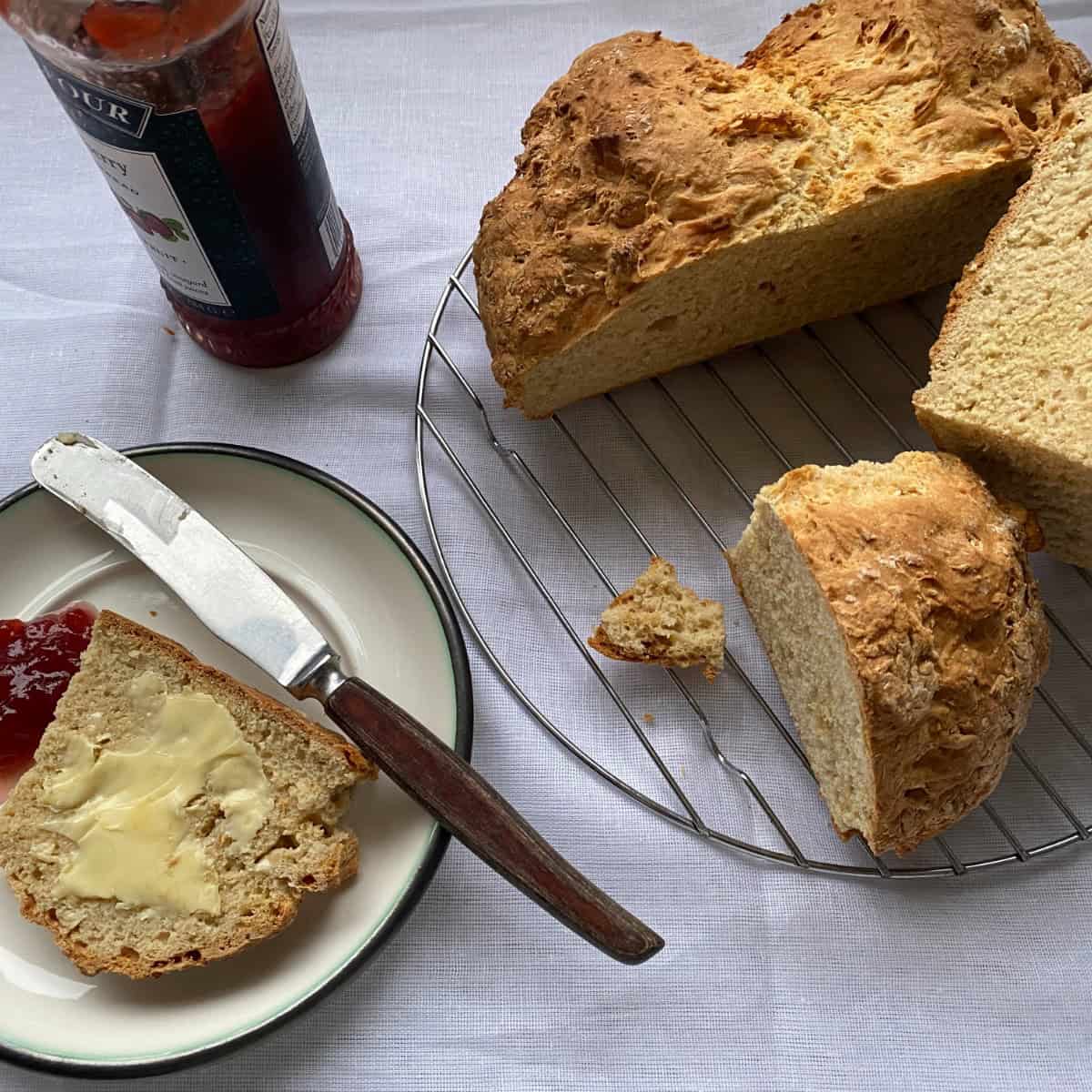 Soda Bread cut into slices. Fresh baked buttermilk soda bread, buttered and with strawberry jam.