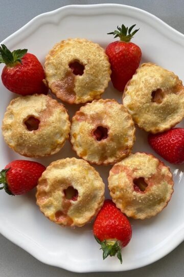 Plate of baked small apple and strawberry pies.