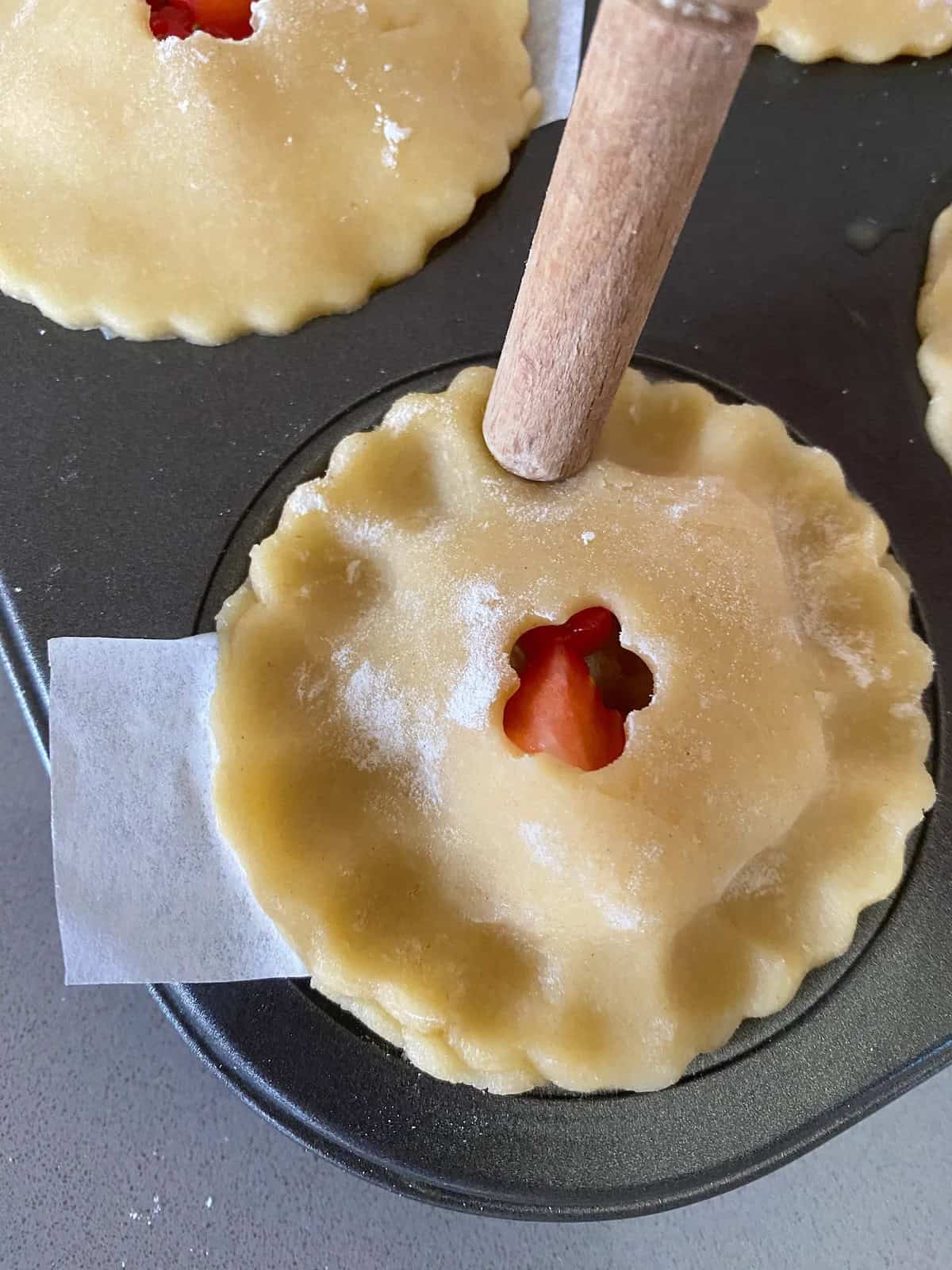 six unbaked fruit pies in a baking tin. small unbaked strawberry and apple tart.