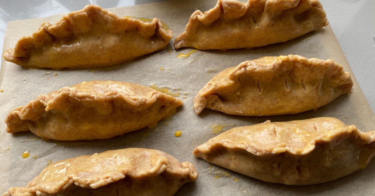 Unbaked vegetable and lentil pasties on a baking tray. 