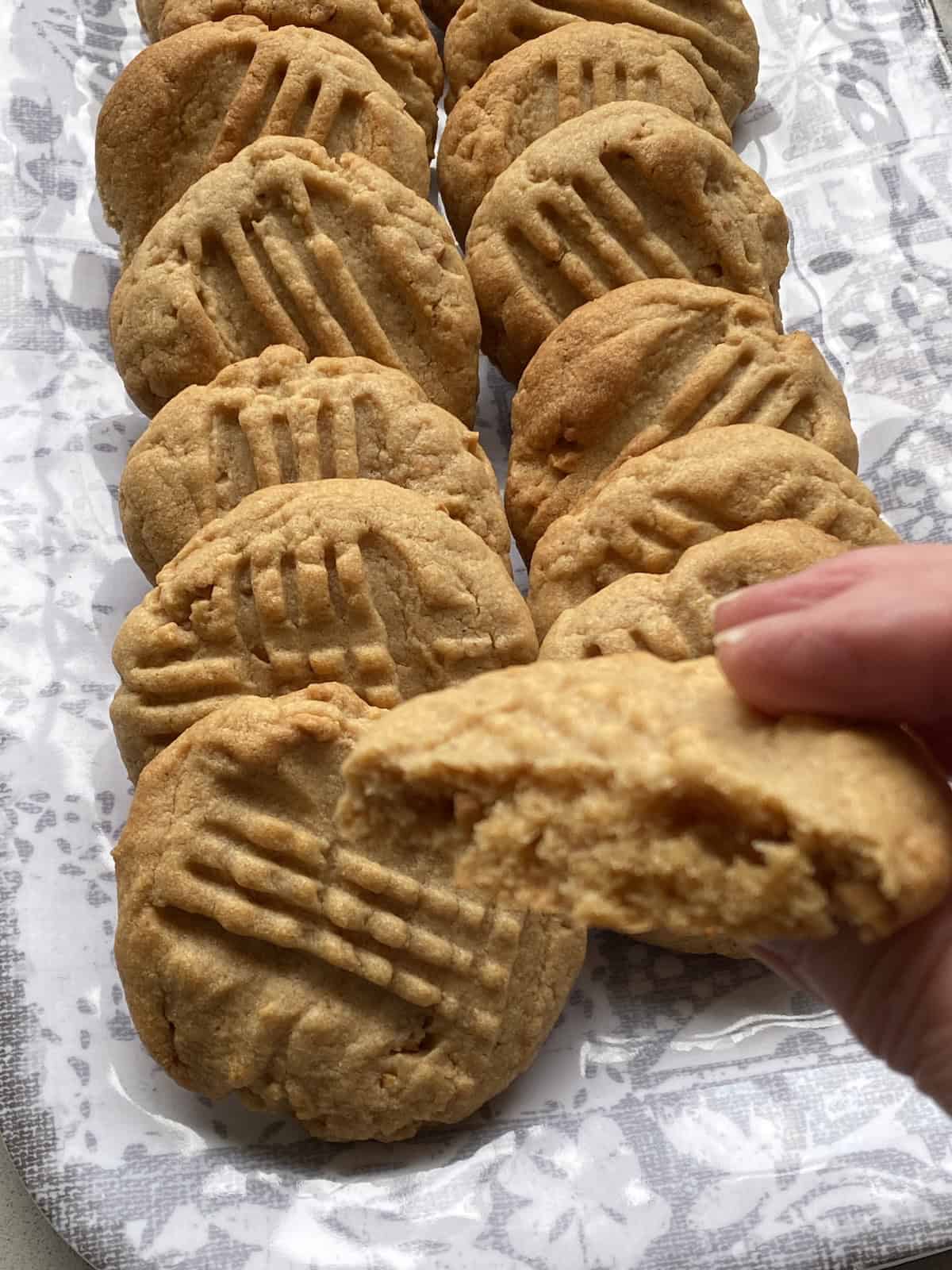 Chunky Peanut Butter Cookies on a tray, with one being held.
